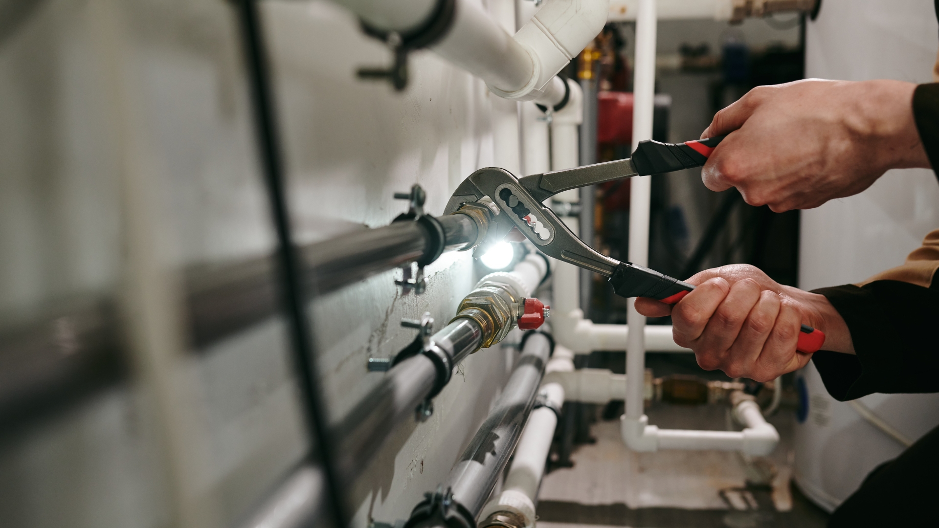 Do you need help with Plumbing? Picture of a man with a tool fixing a pipe.