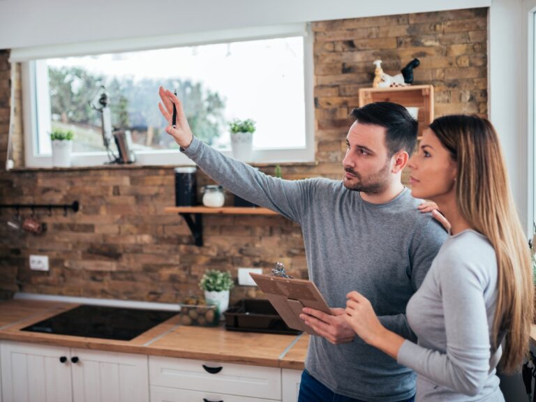 Two individuals are pondering, What Types of Home Improvements Are Tax Deductible? in their new kitchen.