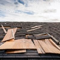 Damaged shingle roof with exposed wood sheathing.