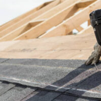 Worker nailing roofing felt on a house roof.