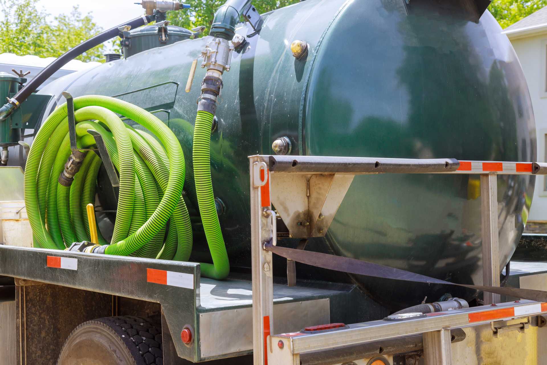 A sewage tank truck parked next to a house.