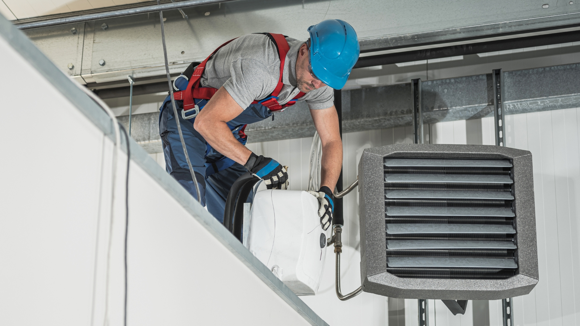 A professional Caucasian HVAC technician in his 40s diligently installing air and water heaters inside a newly constructed warehouse. With expertise in heater repair services, commercial HVAC systems, air conditioning, and furnaces, he ensures efficient central heating for the premises. Equipped with the necessary technology, devices, and equipment, he applies his industry knowledge to provide high-quality installations. This skilled worker embodies the professionalism and dedication required in his line of work. For those pondering the question, 'Should I try to fix my own water heater?' this image highlights the importance of relying on experienced technicians for optimal results and safety.